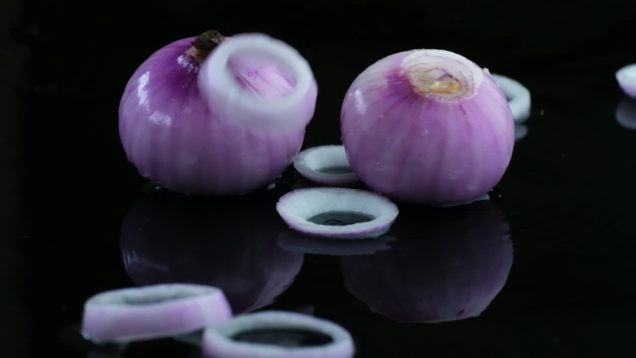 Rewind clip of fresh onion rings falling on bulbs of red onion