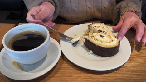 manos mayores comiendo pastel con café