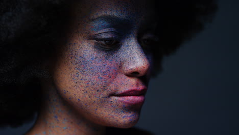 retrato de cerca de una hermosa mujer afroamericana que usa pintura exótica para la cara arte corporal mujer misteriosa con maquillaje colorido luz parpadeante en fondo oscuro concepto de expresión creativa