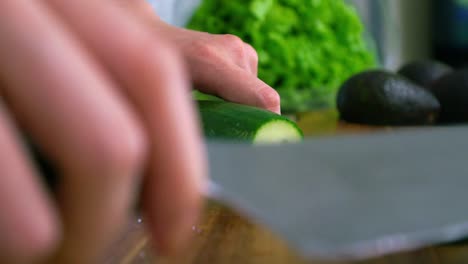 cutting the tip of a green organic cucumber