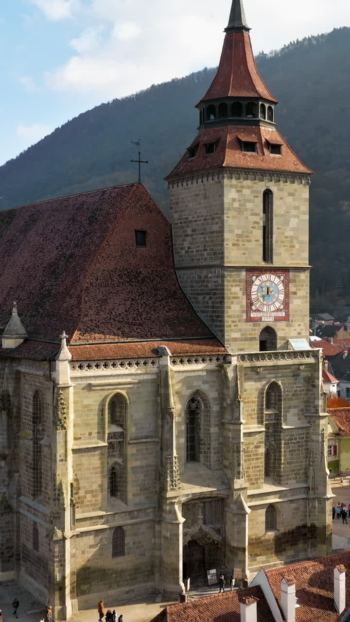 Aerial drone view of The Black Church in the city center of Brasov, Romania surrounded by mountains. Vertical