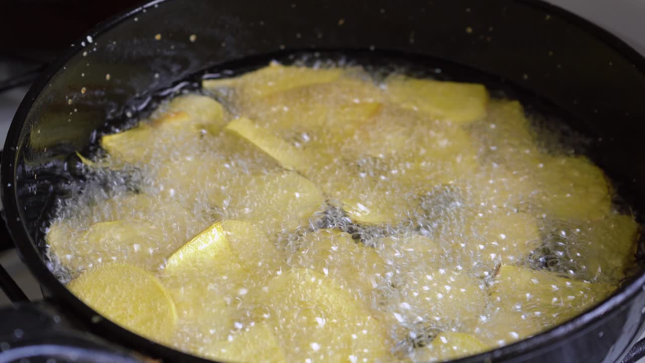 Nærbillede af boblende madolie i en pande, der steger søde kartoffelchips