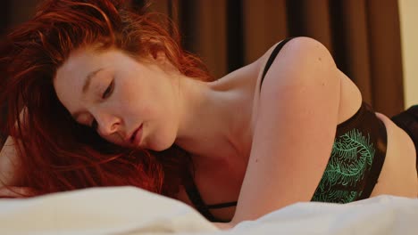 A-beautiful-redheaded-woman-lies-on-her-belly-in-bed