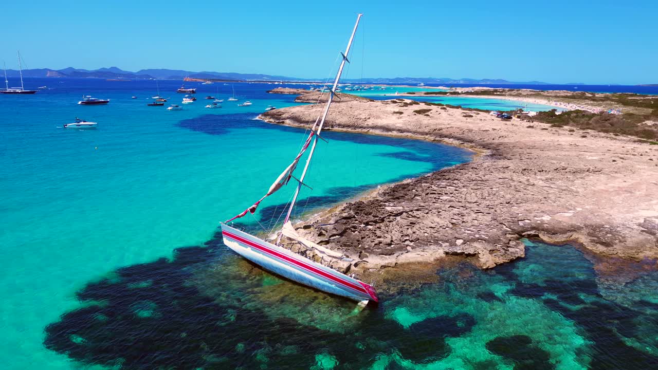 Barca a vela incagliata su una scogliera vicino alla costa dell'isola di Formentera, Spagna, durante una giornata estiva di sole. Bella panoramica aerea con drone.