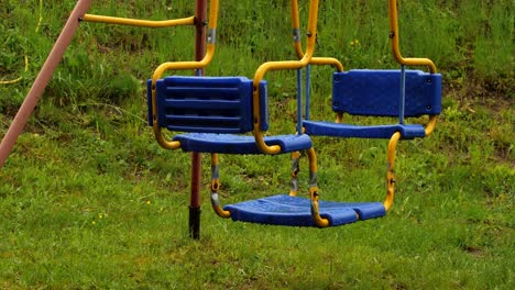 empty swing set hangs still in rain on playground