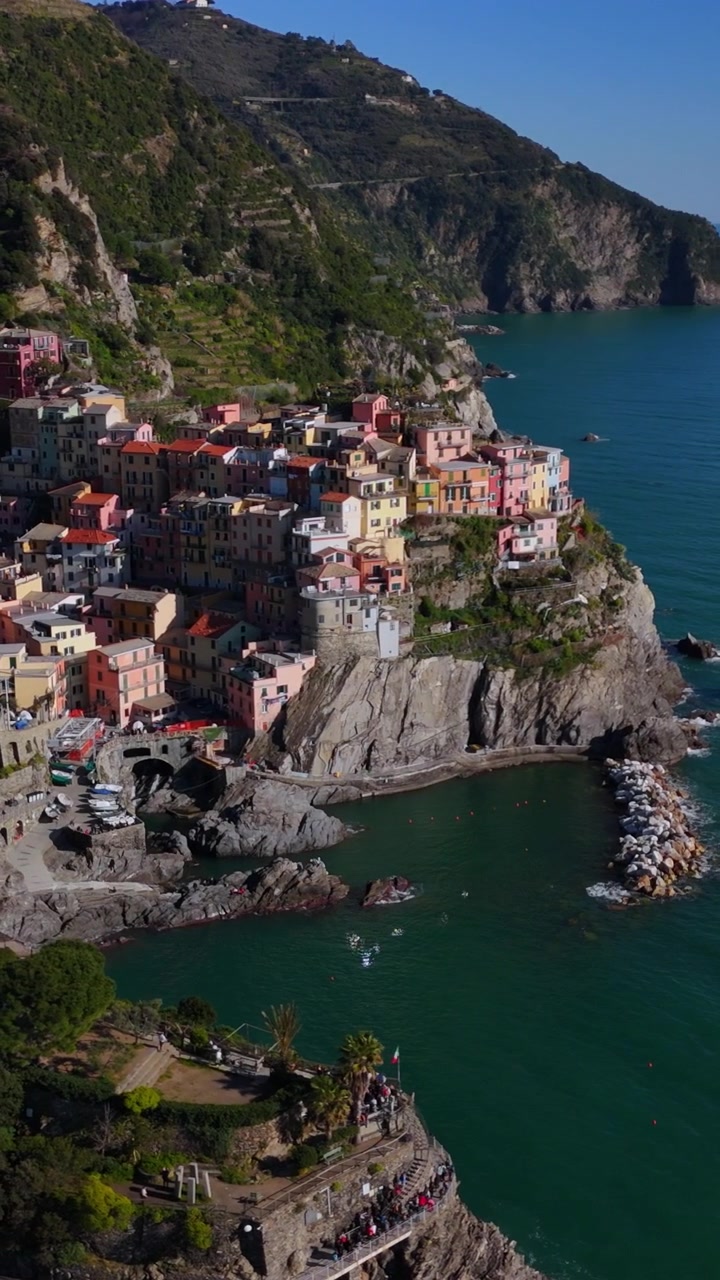 Panoramique aérien vertical révélant le promontoire rocheux de Manarola s'avançant dans la mer ouverte