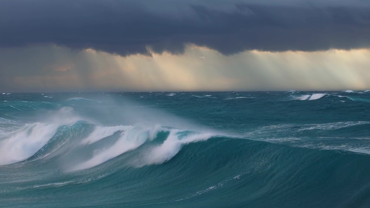 Poderosas olas del océano bajo un cielo tormentoso con rayos de sol