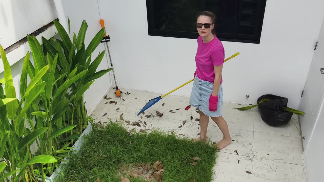 mujer barriendo hojas en el patio