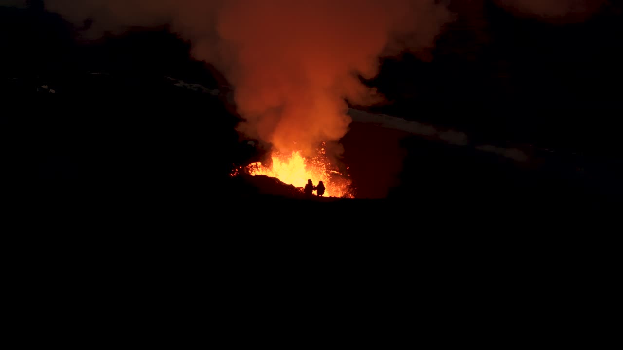 아이슬란드에서 2023년 화산 폭발로 밤에 산꼭대기에 서 있는 사람들