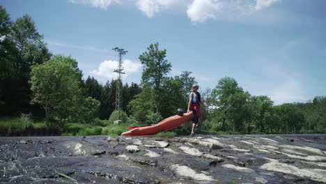 kayaker walking on weir and pulling kayak, low water level on sazava river in czech republic, side view
