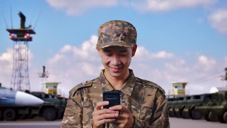 close up of asian man soldier using smartphone while standing at military camp