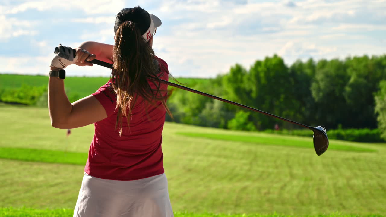 Woman in white skirt playing golf on a grass field on a sunny day