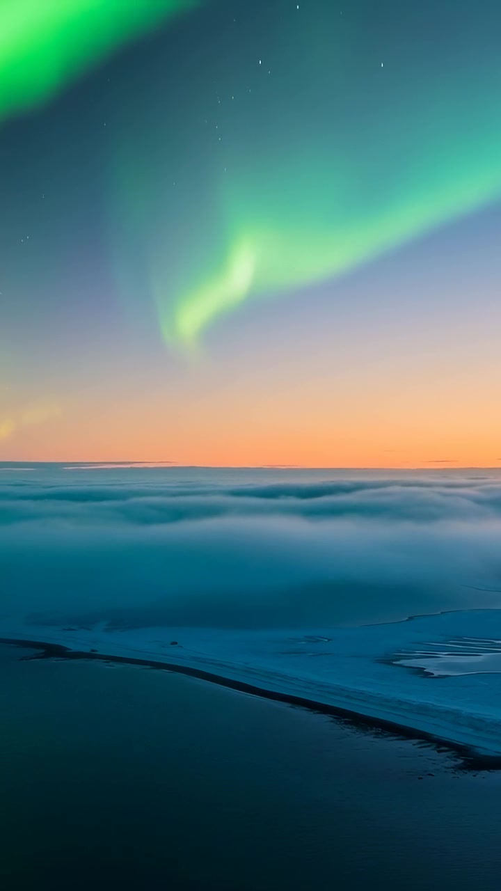 Video verticale: Crepuscolo che si affievolisce con nastri di aurora boreale che si muovono su una baia ghiacciata con banchi di nebbia e stelle.