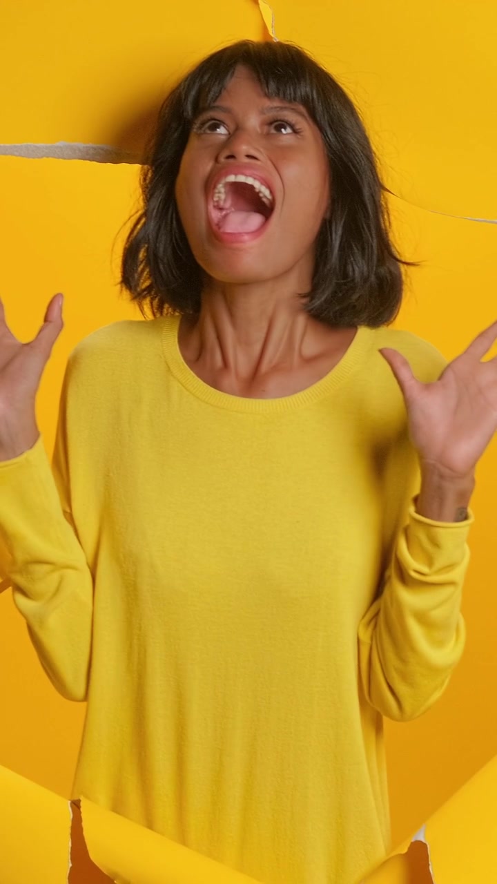 Shocked asian woman screaming and gasping on yellow torn paper background