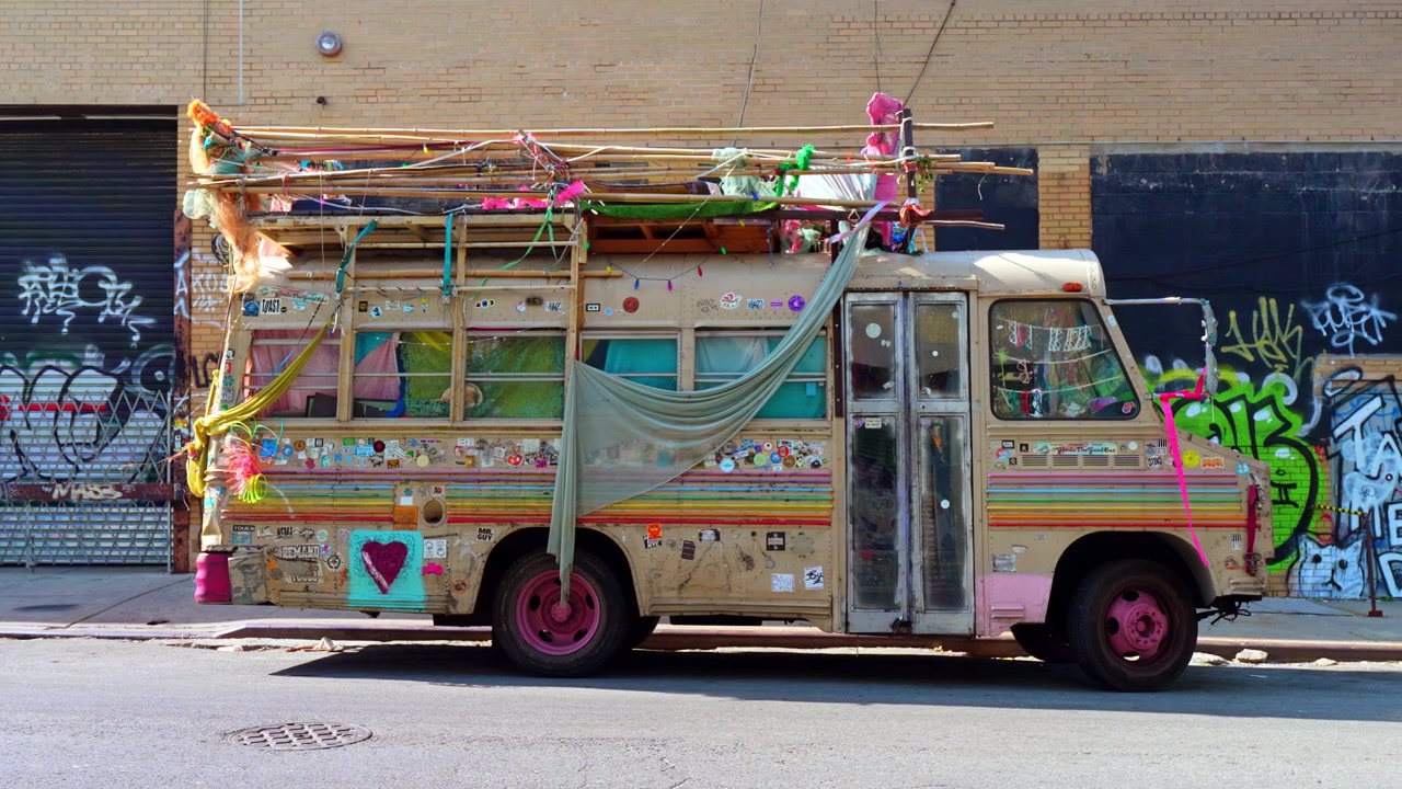 New York, VS, 26 mei 2026: Versierde vintage bus geparkeerd in een straat met graffiti, Brooklyn, New York. Zijaanzicht met kleurrijke stoffen, stickers, roze wielen en bamboe imperiaal