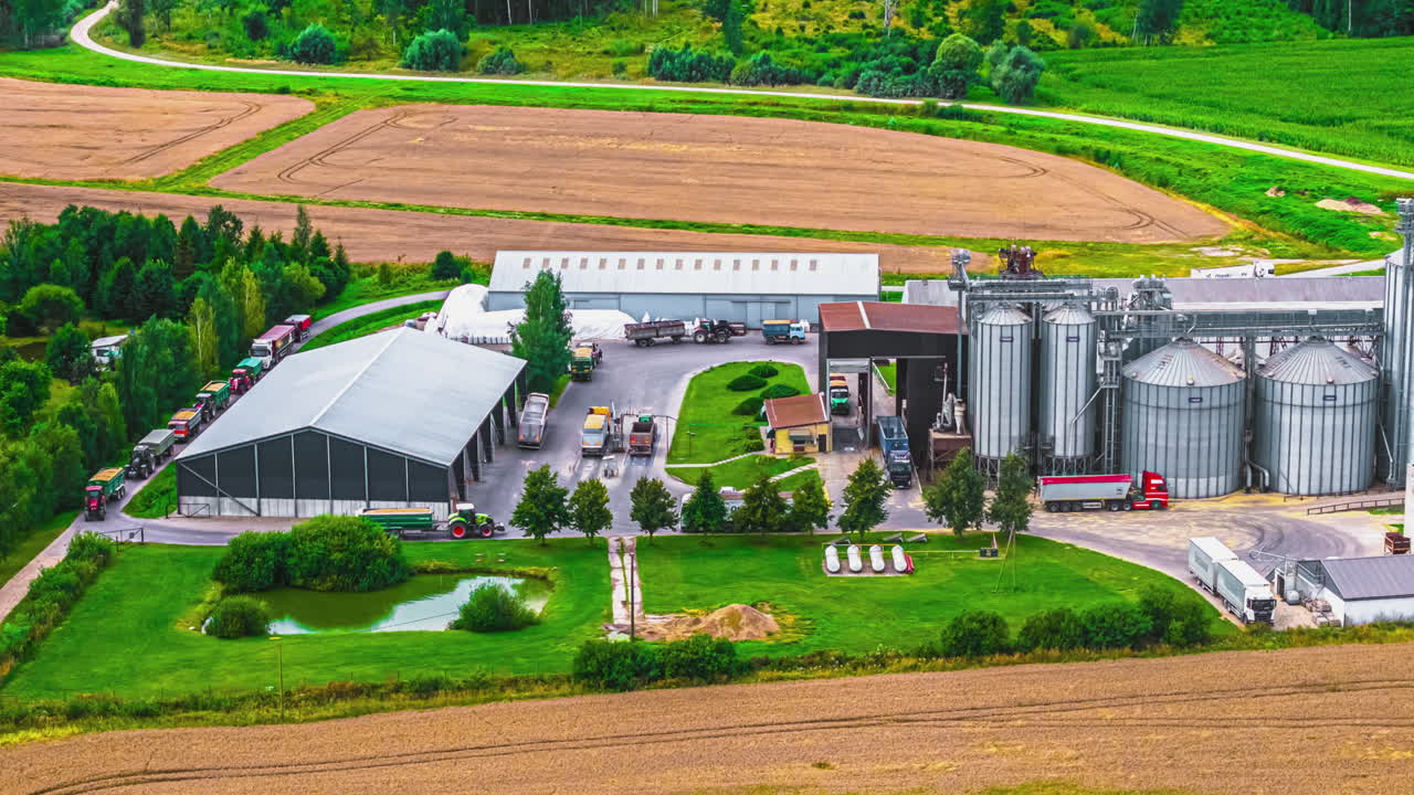 Side perspective of semi trucks waiting to offload grain at storage silo facility