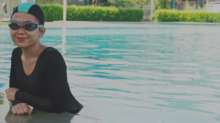 Young Asian Woman Wear Swim Cap And Goggle, Standing In ThePool And Looking At The Camera