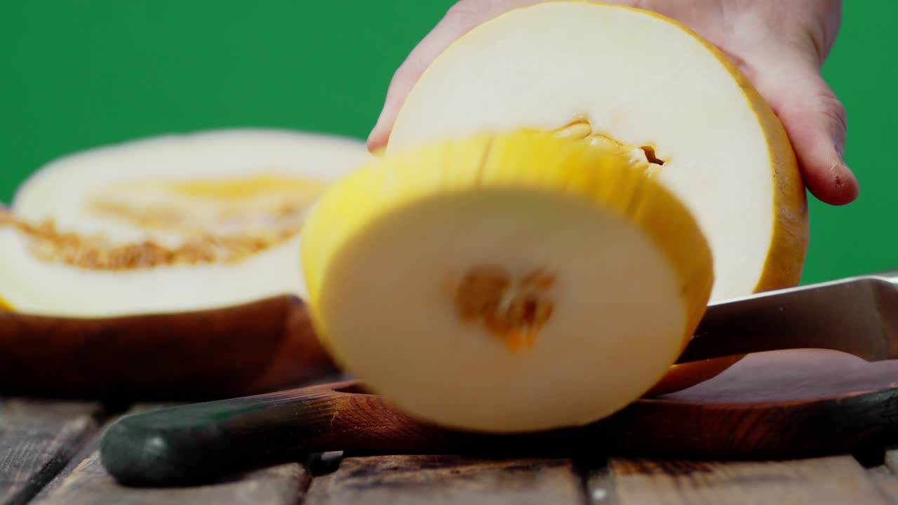 manos masculinas cortando un melón maduro en rebanadas redondas.