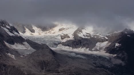 low clouds over the snow capped mountains in glacier bay national park, alaska