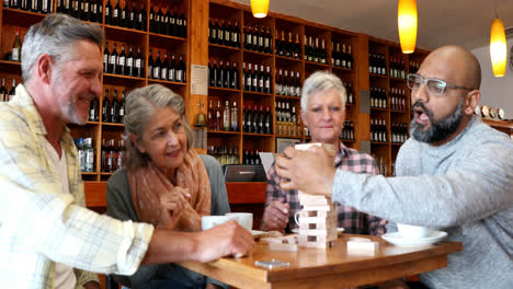 amigos felices jugando al juego de jenga mientras toman una taza de café 4k