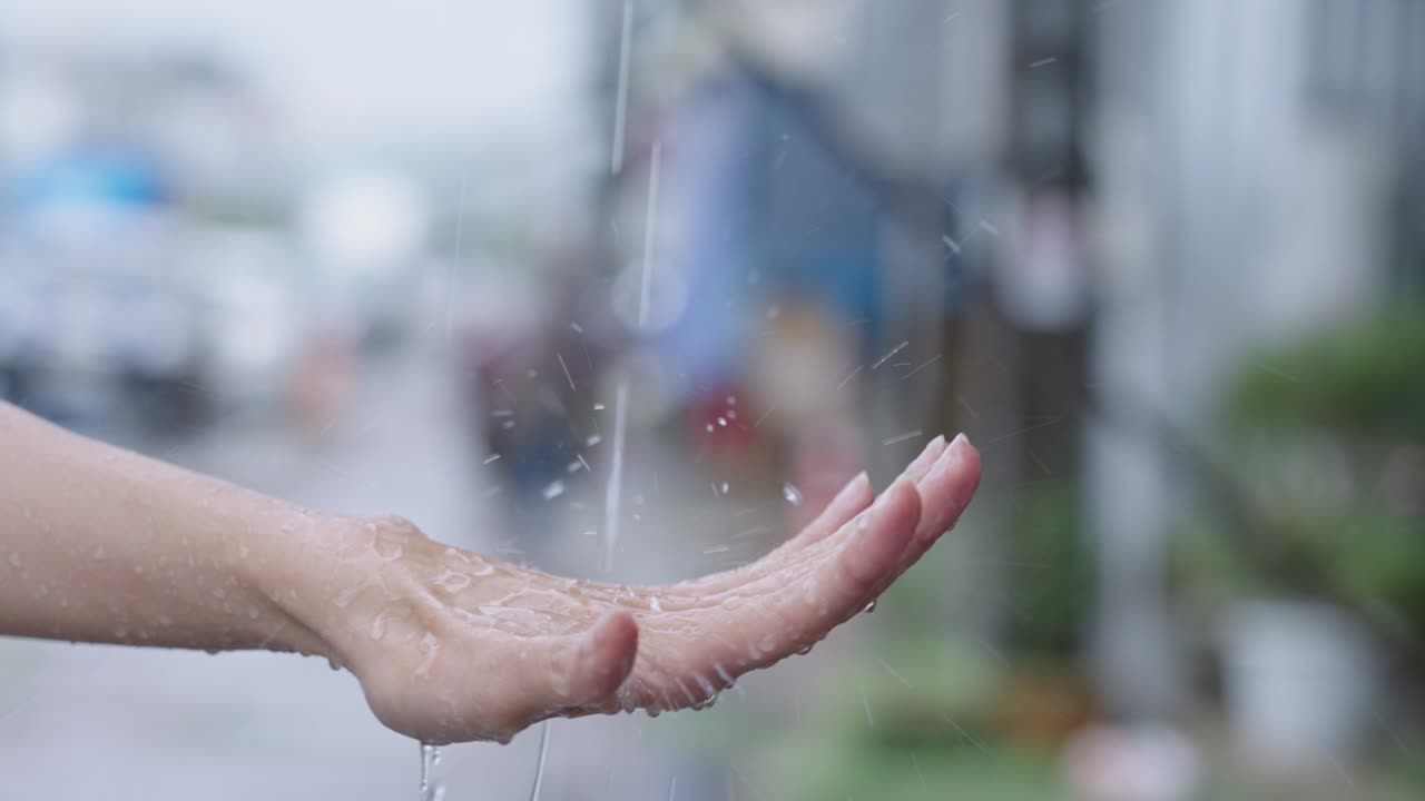 girl hand catches rain drops, touch the season, rains on female Palm, rainy season slow motion, on the street side, temperature changes humidity air condensation, weather fore cast, rain cats and dogs