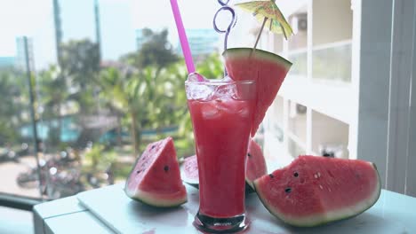 big juicy watermelon pieces lie on table near tall glass