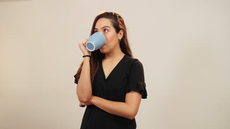 una mujer joven bebiendo y disfrutando de su café.
