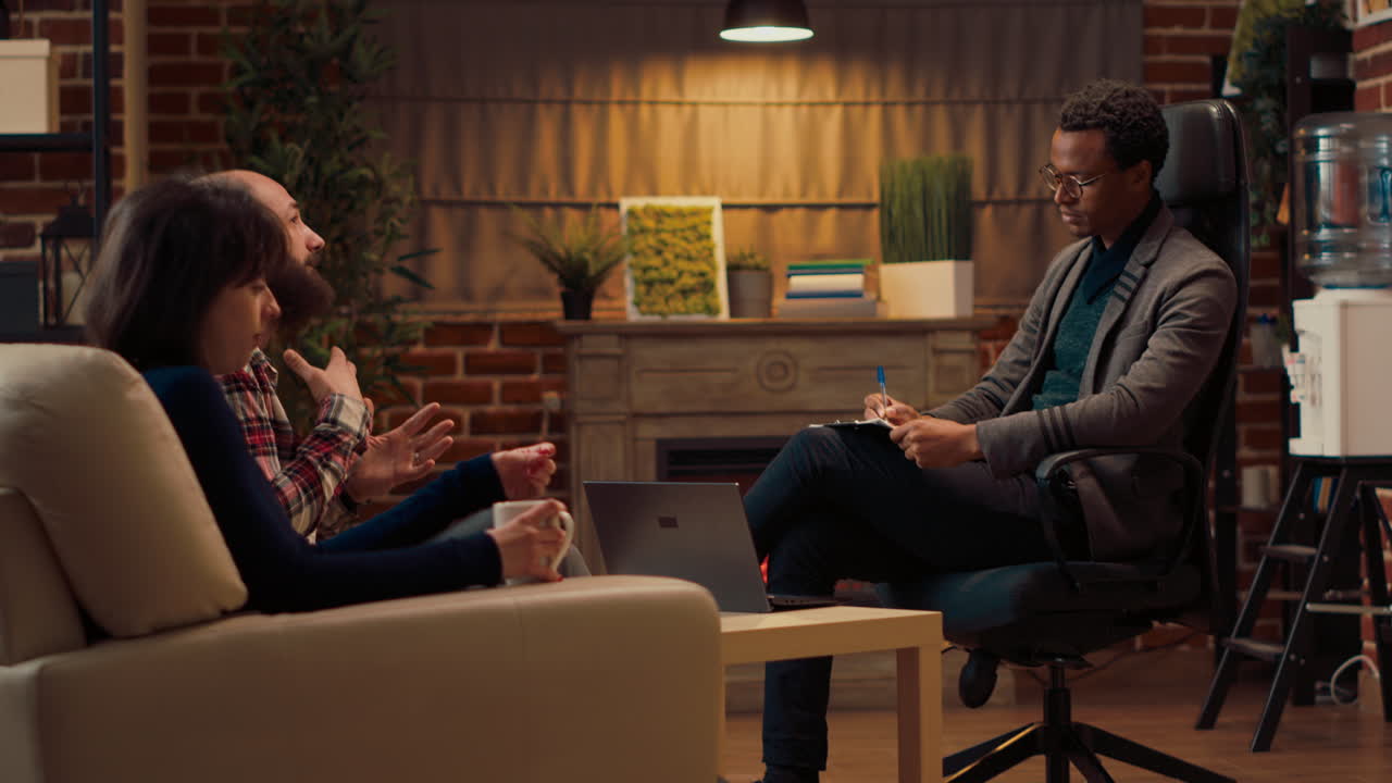 Male therapist listening to husband and wife at couple counseling session