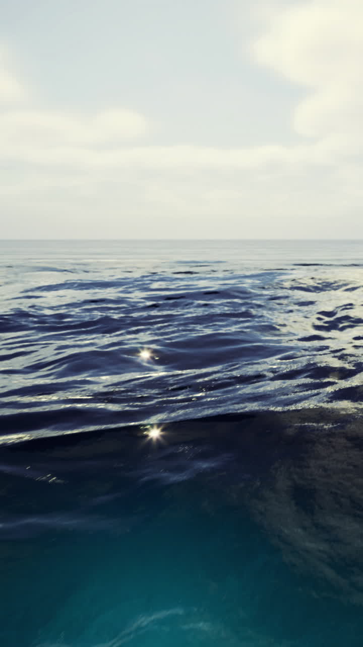 Vast blue waves roll gently under a serene sky at midday