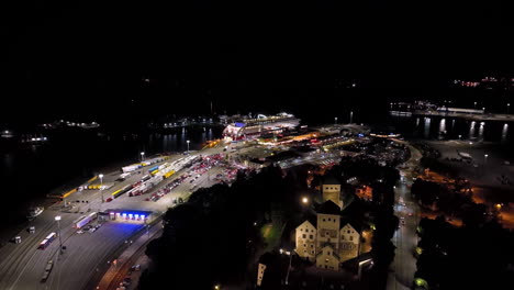 aerial night view of a busy port with ferry, trucks, and castle