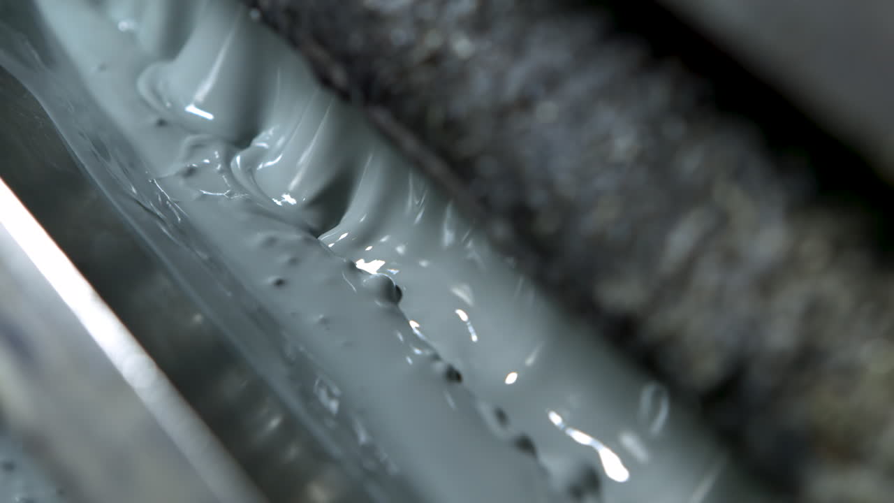 Extreme closeup of bubbling light green-grey paint in an old and grungy wallpaper printer