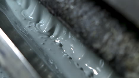 extreme closeup of bubbling light green-grey paint in an old and grungy wallpaper printer