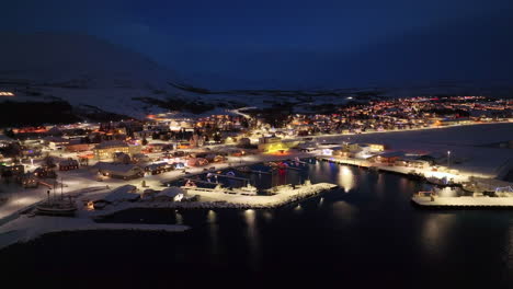 Breite-Luftschwenk-Nachtdrohnenaufnahme-Einer-Beleuchteten-Stadt-In-Island-Im-Winter