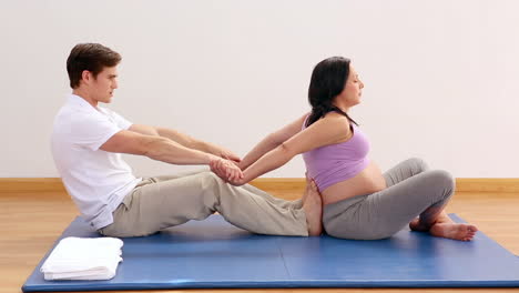 physiotherapist pulling his pregnant patients arms