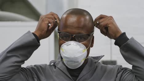 african american male car mechanic putting a face mask on