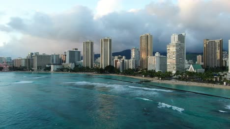 toma panorámica de la playa de waikiki en un día tormentoso tropical, olas rodando mientras los surfistas esperan