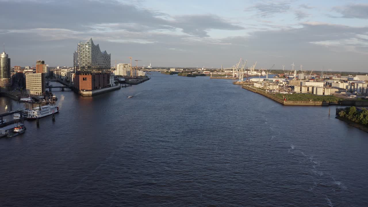 Drone view of contemporary town with harbor located on shores on river against cloudy sky
