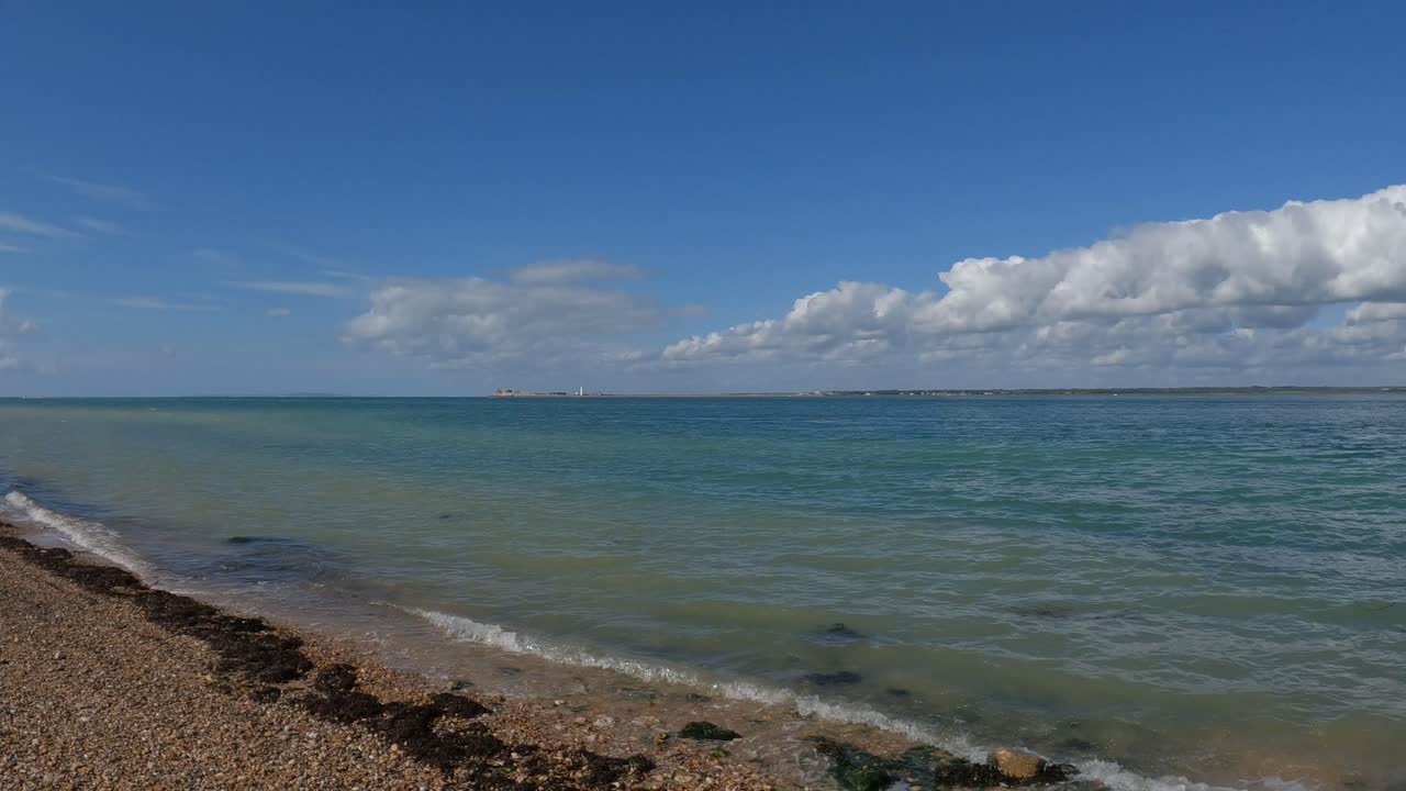 Onde di acqua cristallina che accarezzano delicatamente la spiaggia di ciottoli arancioni nell'Isola di Wight