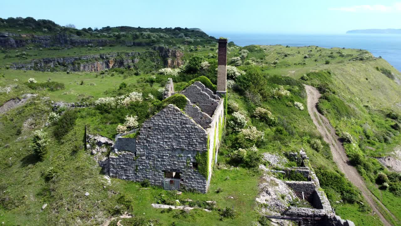 abandonado cubierto de hiedra desolada campiña histórica fábrica de ladrillos costeros galeses molino vista aérea órbita de izquierda a trasera