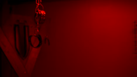 handcuffs on the ceiling in a red bondage room