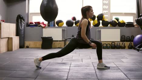 Young-beautiful-athletic-female-brunette-doiung-lunges-workout-at-the-gym.-Getting-ready-for-summer.-Fitness-and-wellbeing.