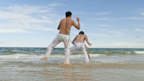 two men dancing capoeira on the beach