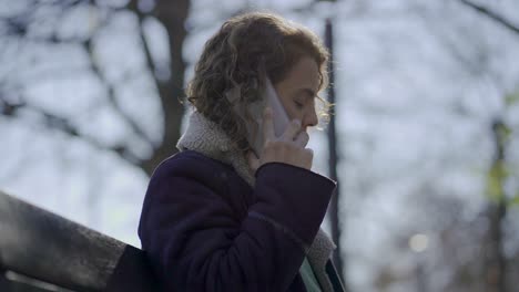 Side-view-of-curly-woman-talking-on-smartphone