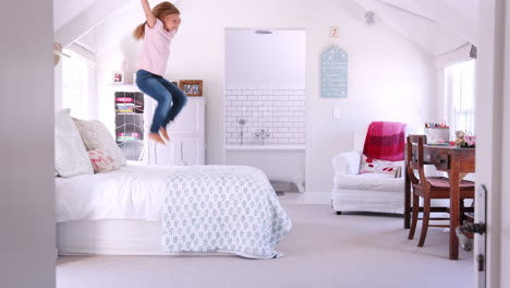 happy young white girl jumping on the bed in her bedroom