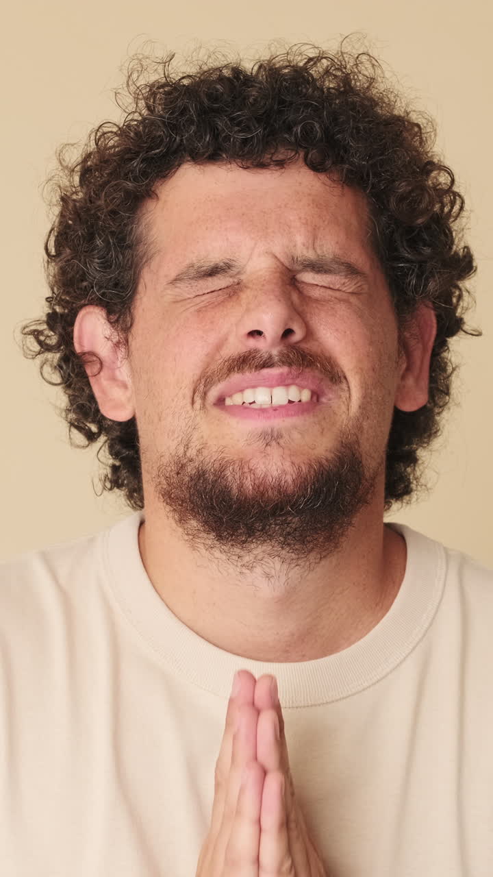 Jovem com cabelo encaracolado orando com os olhos fechados