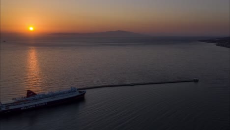 drone sunrise view of the mediterranean sea over water with mountains and ferry to athens in lesvos, greece - mitilini harbor aerial hyperlapse