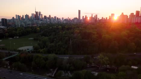 Vista-Aérea-De-4k-Del-Parque-Verde-Que-Muestra-El-Tráfico-Y-La-Ciudad-De-Toronto-Al-Fondo