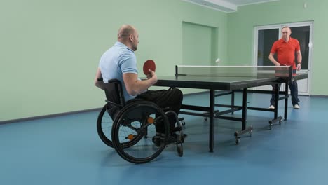 un hombre en silla de ruedas juega al ping-pong. personas con discapacidad juegan al tenis de mesa. rehabilitación de discapacitados. deporte.