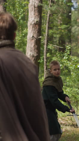 teenage boys train sword strikes with master in sunny pine forest at quest slow motion. historical reconstruction club for children. role playing