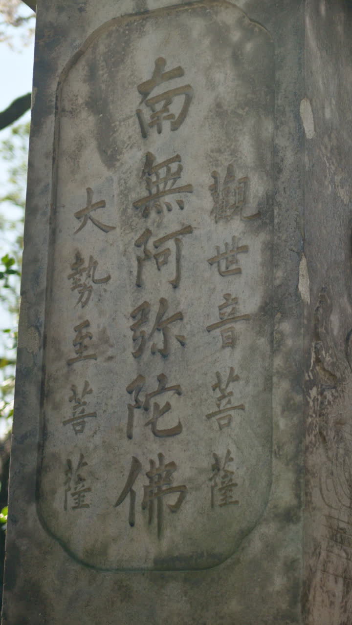 Close up of a stone pillar in the courtyard of the Senso-ji temple in Asakusa, Japan. Vertical. Translation: "Namo Amitabha"